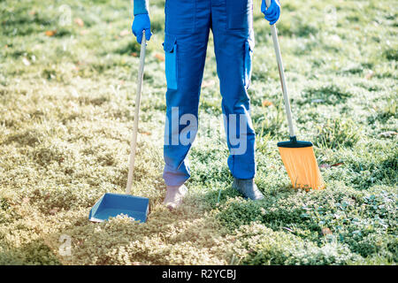Sweeper in uniform with cleaning tools in the garden, cropped image with no face Stock Photo