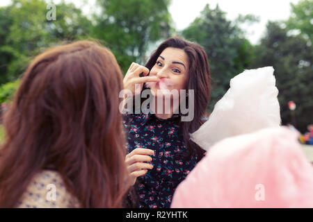 Two sisters making funny faces and mustache while playing and eating cotton candy Stock Photo