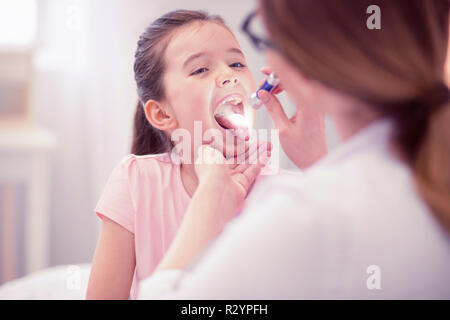 Smiling general practitioner pouring some medication for sick girl Stock Photo