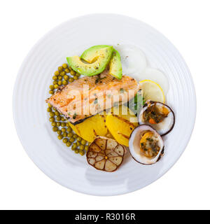 Top view of baked trout fillet served on white plate with vegetables, avocado and dog cockles. Isolated over white background Stock Photo
