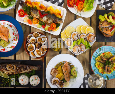 Top view of delicious meals from trout and dog cockles served on wooden table Stock Photo