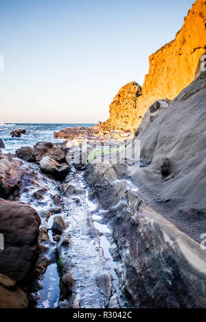 A steep cliff abuts the sea, creating a small inlet in Coos Bay, Oregon. Stock Photo