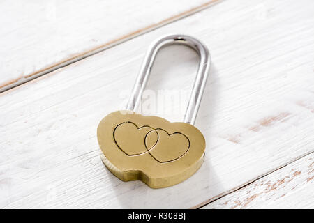 Golden padlock hearts on white wooden background. Stock Photo