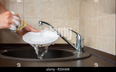 Image of side of man's hands washing transparent mug in sink Stock Photo