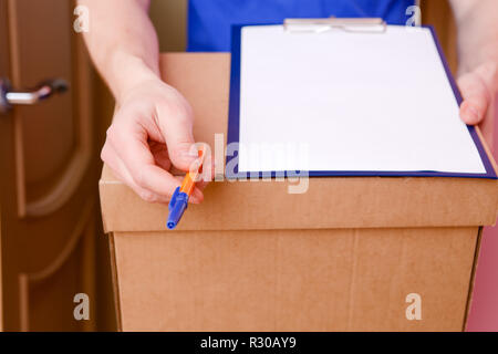 Photo close up of courier with pen, blank sheet of paper, cardboard box Stock Photo
