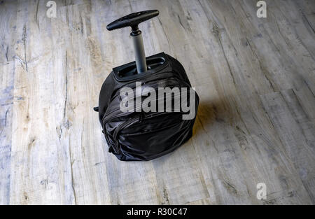 Black laptop bag with an aluminium handle standing on a mid grey laminate floor. Space all around the bag. Stock Photo