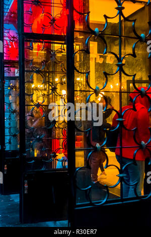 People entering a the gates of a department store in Gran Via, Madrid,  during a wet dark late afternoon on Sunday. Stock Photo