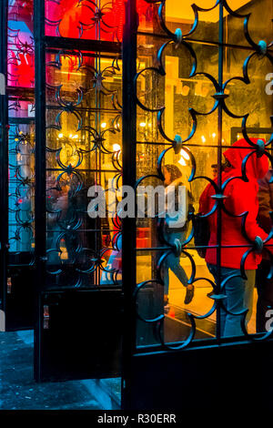 People entering a the gates of a department store in Gran Via, Madrid,  during a wet dark late afternoon on Sunday. Stock Photo