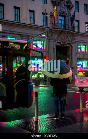 People in Gran Via, Madrid, walking in the rain during a dark late afternoon on Sunday. Stock Photo