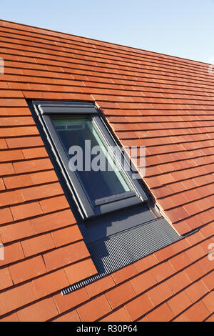 Velux style roof light window in a traditional plain clay tile house roof Stock Photo