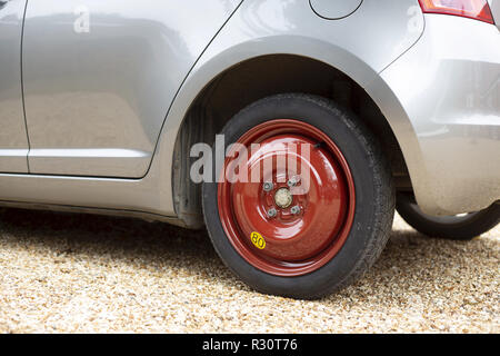 Space saver wheel and spare tyre or tire fitted to a small car Stock Photo