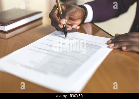 African american man signing contract, black man hand putting signature on official document, biracial clients customers couple make purchase or sign  Stock Photo