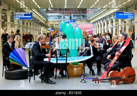 London, UK. 21st November, 2018. Cello, is it me you’re looking for? East Midlands Trains partnered with the Royal Philharmonic Concert Orchestra to introduce its Found It! service, a completely free web-based platform allowing customers to track and claim lost items. Musicians played with instruments and unusual items that have been left behind on trains, performing at St Pancras Station, London. .   Credit: Oliver Dixon/Alamy Live News Stock Photo