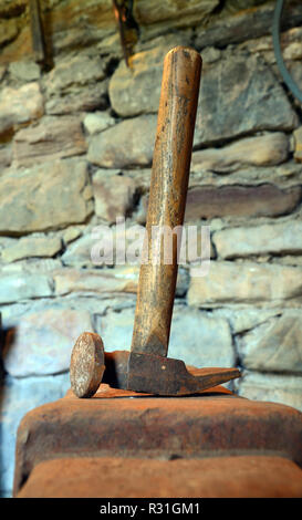 Blacksmiths hammer and anvil in stone shed. Stock Photo