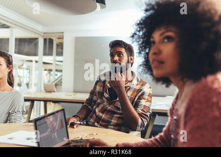 Coworkers sitting in conference room discussing work. business woman in office sitting with laptop in a meeting with coworkers. Stock Photo