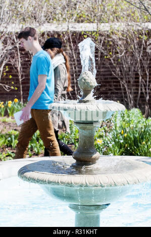 A young couple walking past a decorative water fountain. Stock Photo