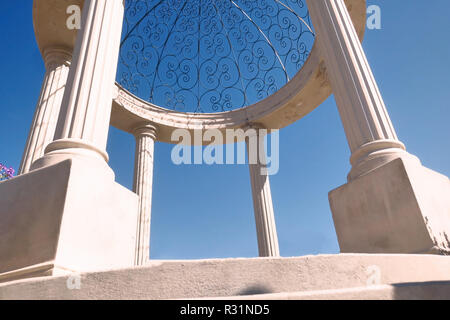 A Round Decorative Concrete With Large Pillars On A Bright Blue