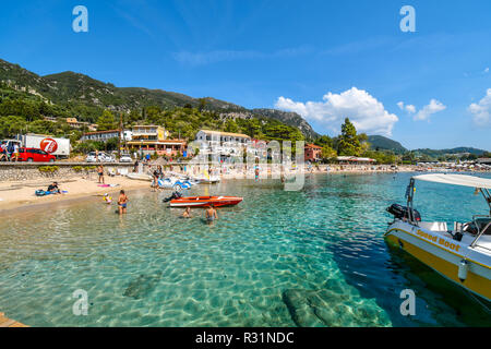 Tourists relax in the clear waters and on the sandy Palaiokastritsa beach on the Aegean island of Corfu, Greece. Stock Photo