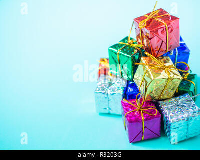 Pile of small colorful gift boxes on light marine blue background with copy space. Top view of many gifts wrapped colorful shiny paper. Stock Photo