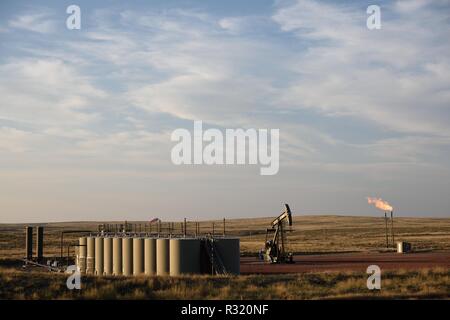 Crude oil well site, production holding tanks, pump jack, and natural gas flaring in the Niobrara shale in Wyoming, USA. Stock Photo