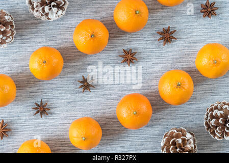 Diagonal rows of oranges, star anise, and pinecones on grey background Stock Photo