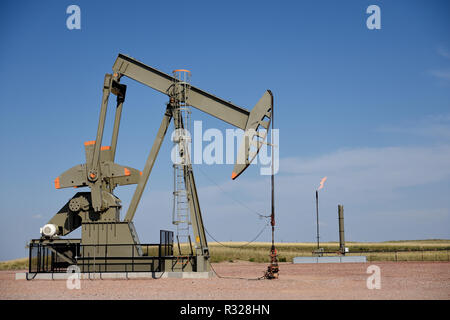 Crude oil production well site pump jack and natural gas flare in the Niobrara shale of Wyoming, with copy space. Stock Photo