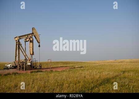 Oil and gas pump jack, well sit and rural fields at sunset, Niobrara shale of Wyoming, with copy space. Stock Photo