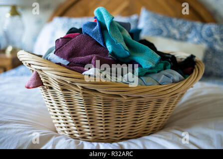 laundry basket of clothes on a bed Stock Photo