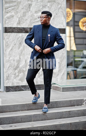 Amazingly looking african american man wear at blue blazer with brooch, black turtleneck and glasses posed at street. Fashionable black guy. Stock Photo