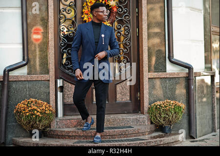 Amazingly looking african american man wear at blue blazer with brooch, black turtleneck and glasses posed at street. Fashionable black guy. Stock Photo