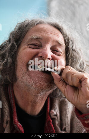 Happy senior man with missing teeth smiling as he bites in to a piece of chocolate. Stock Photo