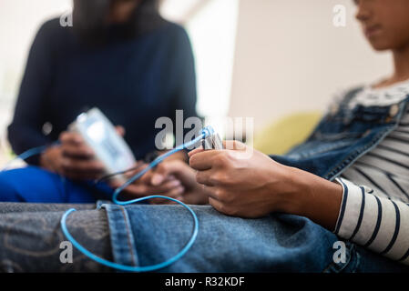 Closeup of teenage girl holding zapper electrodes with bioresonance therapist in background. Stock Photo