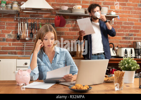 Young couple in savings and home budget concept. Managing finances, taxes using calculator and laptop. Stock Photo