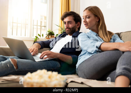Couple using a laptop, relaxing on the sofa. Leisure, internet shopping, video watching concept Stock Photo