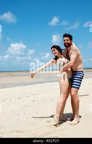 An attractive young couple embracing on an idyllic white sand tropical beach Stock Photo