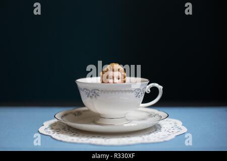 Surreal image of woman (doll) in tea cup. Stock Photo