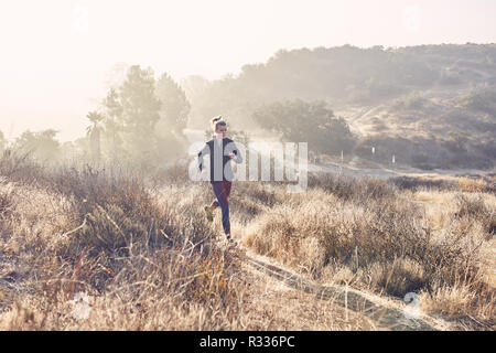 Beautiful Caucasian White Woman Runs on the Trail in the Morning Sunlight Stock Photo