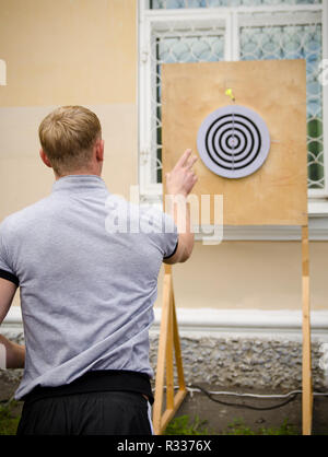 Komsomolsk-on-Amur, Russia - August 1, 2016. Public open Railroader's day. man throws dart at target in amateur competitions Stock Photo