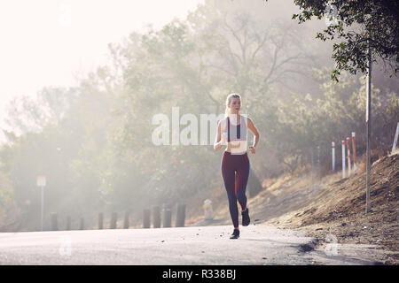 Beautiful Caucasian White Woman Runs Along the Road in the Morning Sunlight Stock Photo