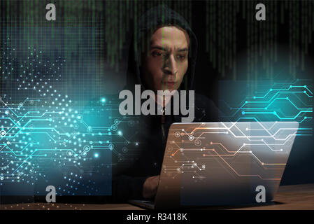 portrait of hacker in black hoodie using laptop, cuber security concept Stock Photo