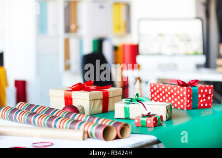 Group of packed gifts in boxes and rolled wrapping paper on table in studio Stock Photo