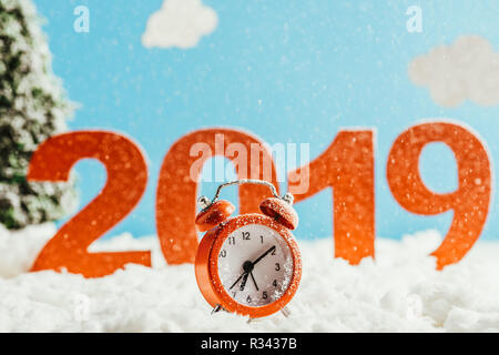 big red 2019 numbers with vintage alarm clock standing on snow on blue background, new year concept Stock Photo