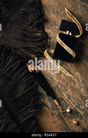 top view of perfume bottle with golden ribbon and decorative black feathers Stock Photo
