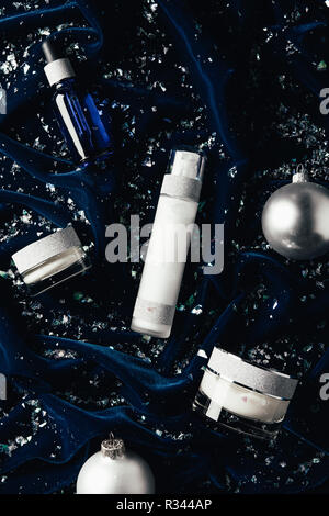 flat lay with serum, beauty cream, lotion and silver christmas balls on velvet surface Stock Photo