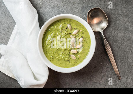 Top view of silver spoon, white cloth and homemade green creamy soup in bowl Stock Photo