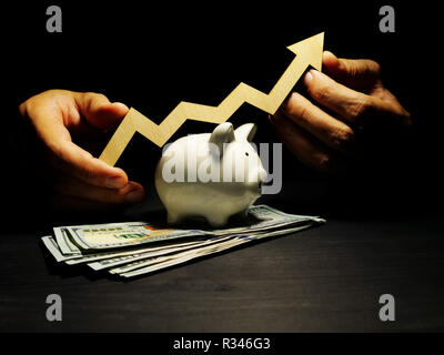 Wealth management. Piggy bank and hands is holding arrow. Money investment. Stock Photo