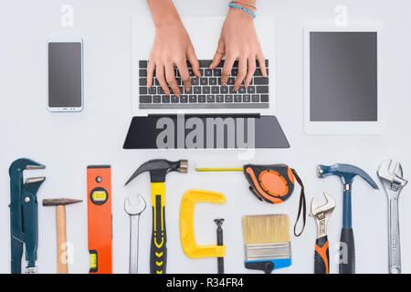 cropped shot of woman using laptop with various tools lying on white Stock Photo