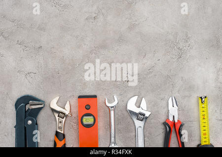 flat lay with row of various tools on concrete surface Stock Photo