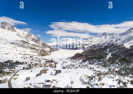 Valley of Engadine in winter season, aerial view. Village of Maloja and alpine lake covered with snow Stock Photo