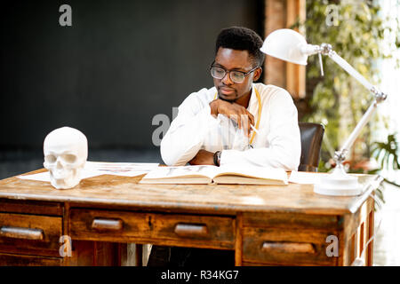 Portrait of a young african ethnicity physician or medical student in uniform during the work or study in the office or classroom Stock Photo